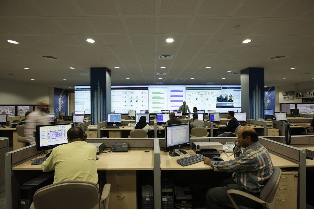 Analysts work at rows of monitors inside a modern cyber security operations centre.